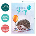 Load image into Gallery viewer, The cover of Tree-Free’s Still Looking Sharp card with lines demonstrating its 5x7 dimensions, along with the following text: “100% PCW recycled paper, proudly made in the USA, sustainably printed on extra-thick card stock”