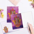 Load image into Gallery viewer, The inside of Tree-Free’s Hamsa Blessings card, with the cover and envelope in the background.
