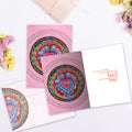 Load image into Gallery viewer, The inside of Tree-Free’s Heart Window Mandala card, with the cover and envelope in the background.