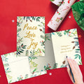 Load image into Gallery viewer, The inside of Tree-Free’s Peace Joy Watercolor Holiday Card card, with the cover and envelope in the background.