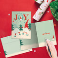Load image into Gallery viewer, The inside of Tree-Free’s Joy Gnomes Holiday Card card, with the cover and envelope in the background.