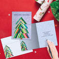 Load image into Gallery viewer, The inside of Tree-Free’s Navidenas Tree card, with the cover and envelope in the background.