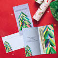 Load image into Gallery viewer, The inside of Tree-Free’s Navidenas Tree card, with the cover and envelope in the background.