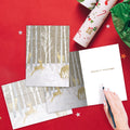 Load image into Gallery viewer, The inside of Tree-Free’s Silent Wood Holiday Card card, with the cover and envelope in the background.
