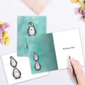 Load image into Gallery viewer, The inside of Tree-Free’s Penguin Pile card, with the cover and envelope in the background.

