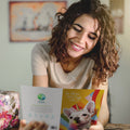 Load image into Gallery viewer, Lifestyle image(s) featuring Tree-Free’s Unicorn And Rainbows Dog card
